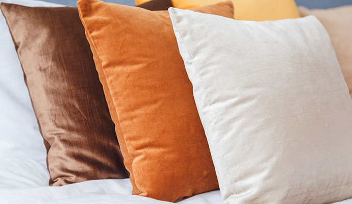 Professionally cleaned decorative velvet pillows on a bed