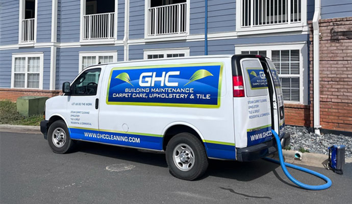 A white GHC Building Maintenance service van parked in front of an apartment.